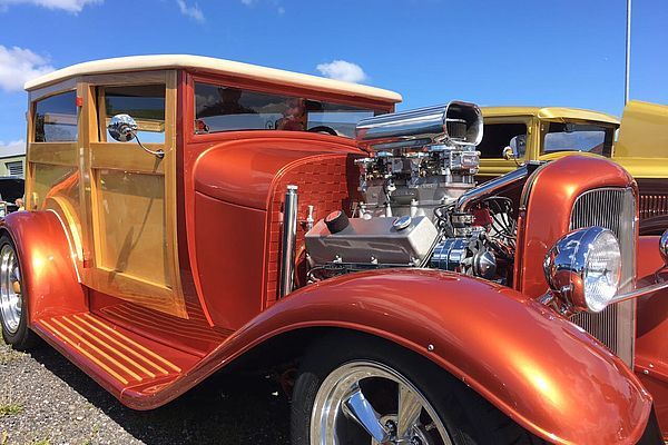 Ein roter Oldtimer steht neben weiteren Oldtimern