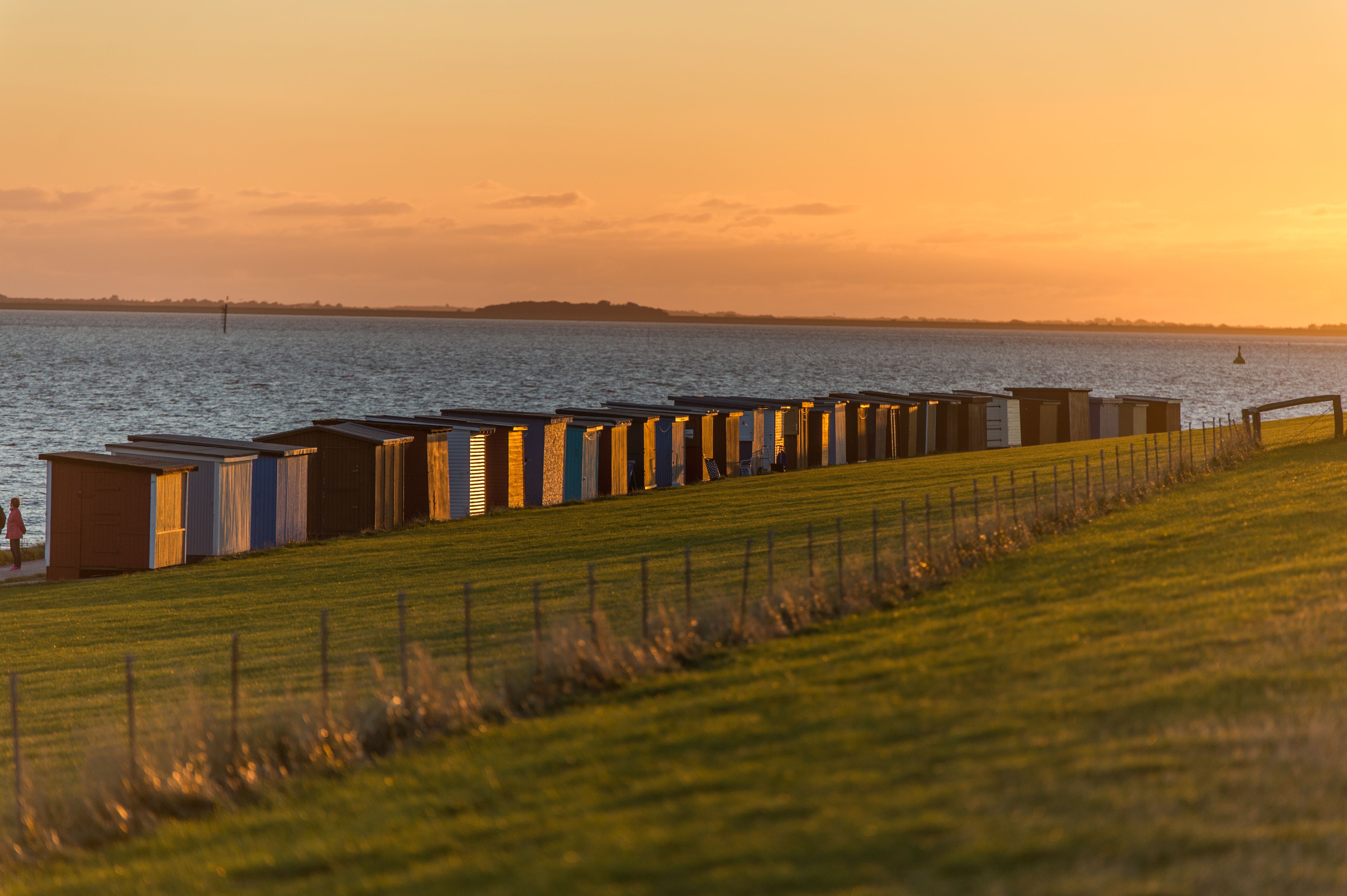 Grünstrand mit Badebuden bei Sonnenuntergang